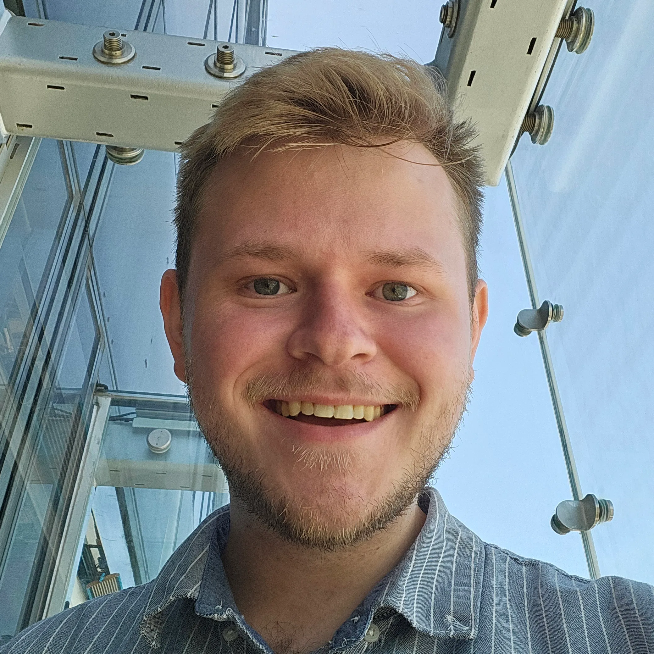 Bryce Terry smiling, photographed from below against a glass and steel canopy